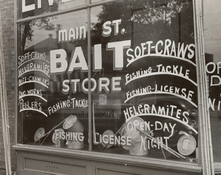 A store window hand-lettered with fishing tackle and bait advertisements
