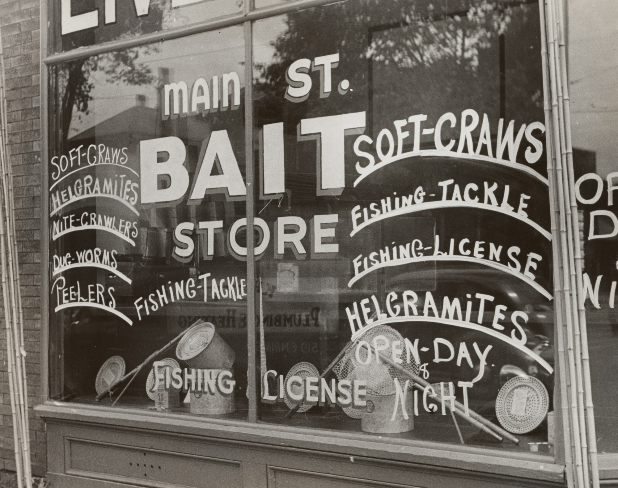 A store window hand-lettered with fishing tackle and bait advertisements