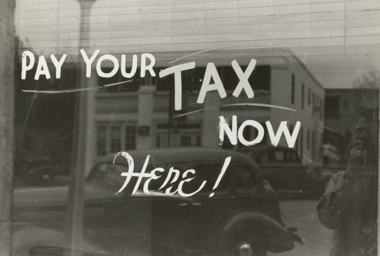 Hand-lettered sign painted on a shop window, a parked car visible through the glass
