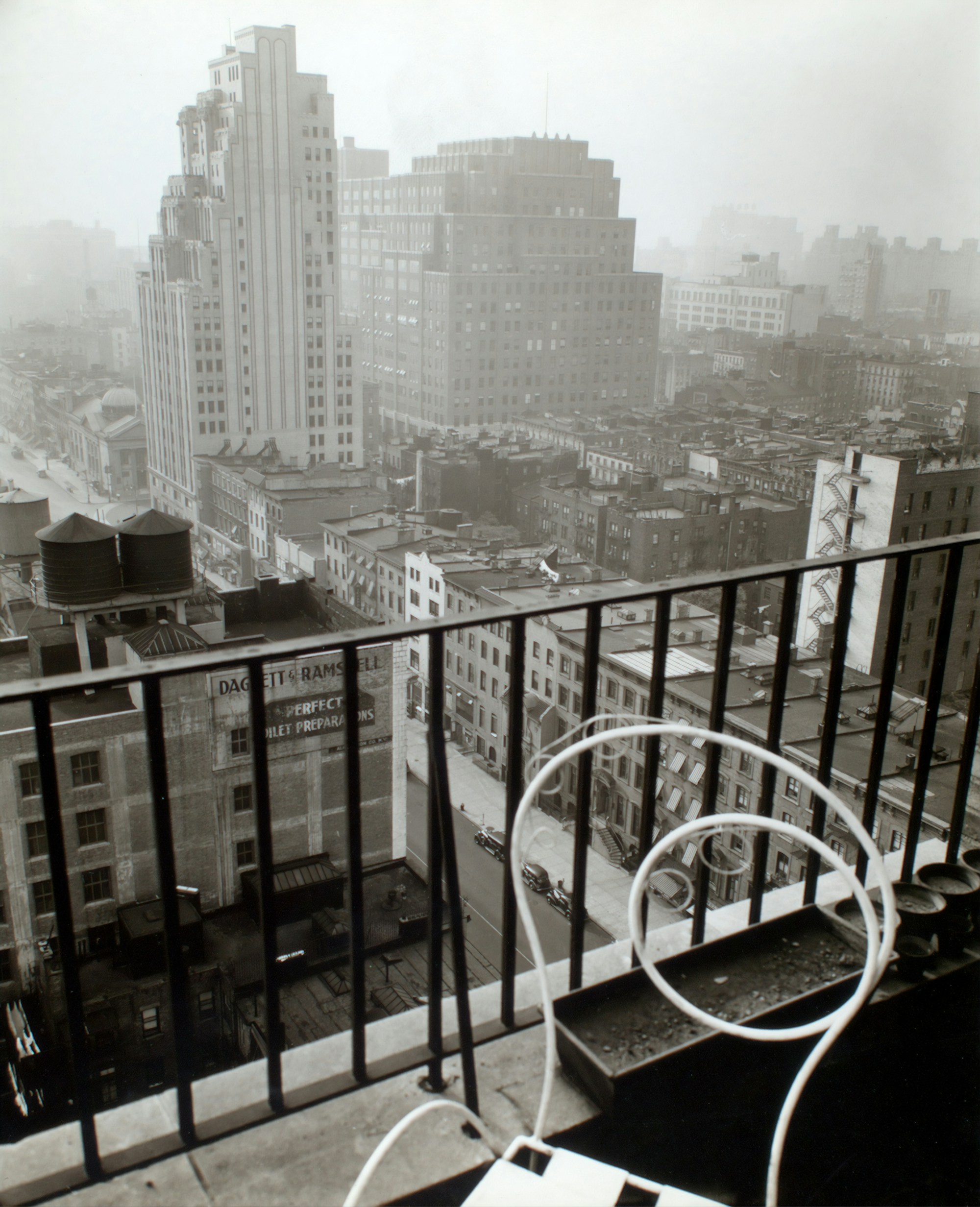 Rooftops, water towers and city blocks seen over an iron railing
