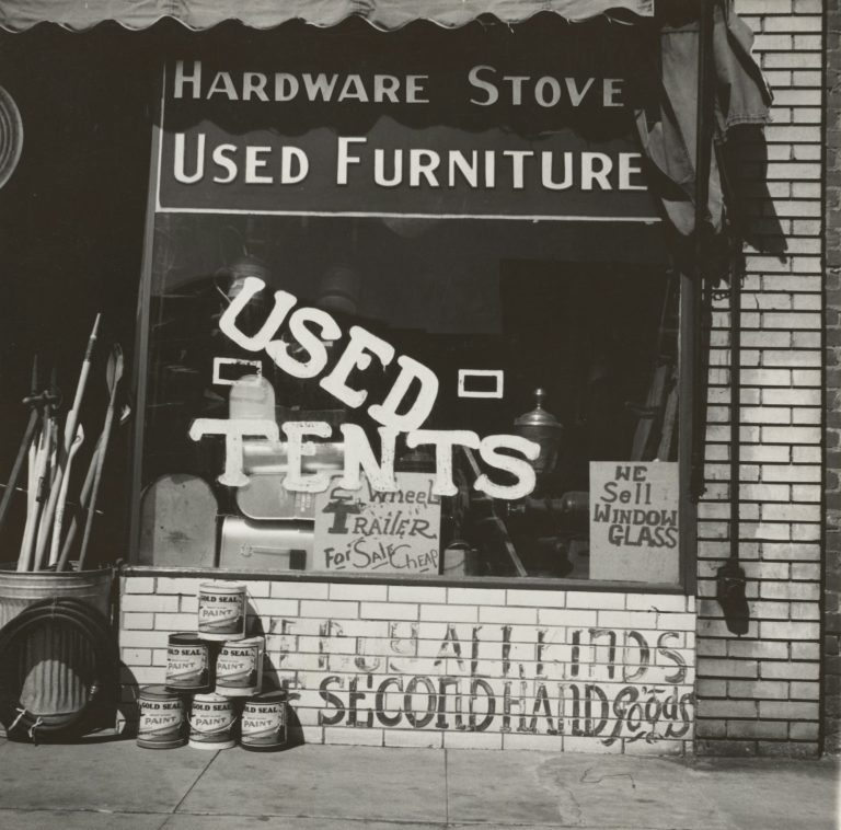 A junk shop window advertising used furniture, used tents and second-hand goods
