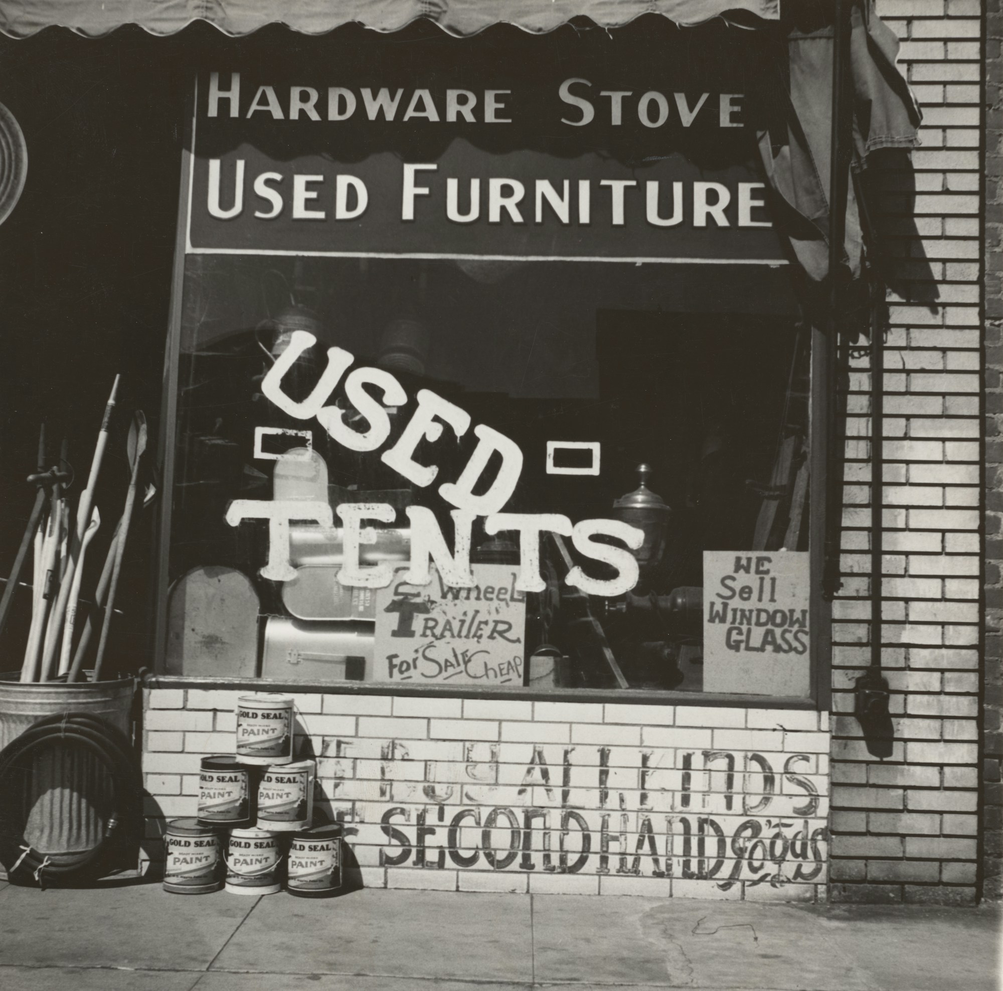 A junk shop window advertising used furniture, used tents and second-hand goods